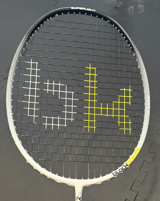 Badminton racquet with white and yellow prints on black strings