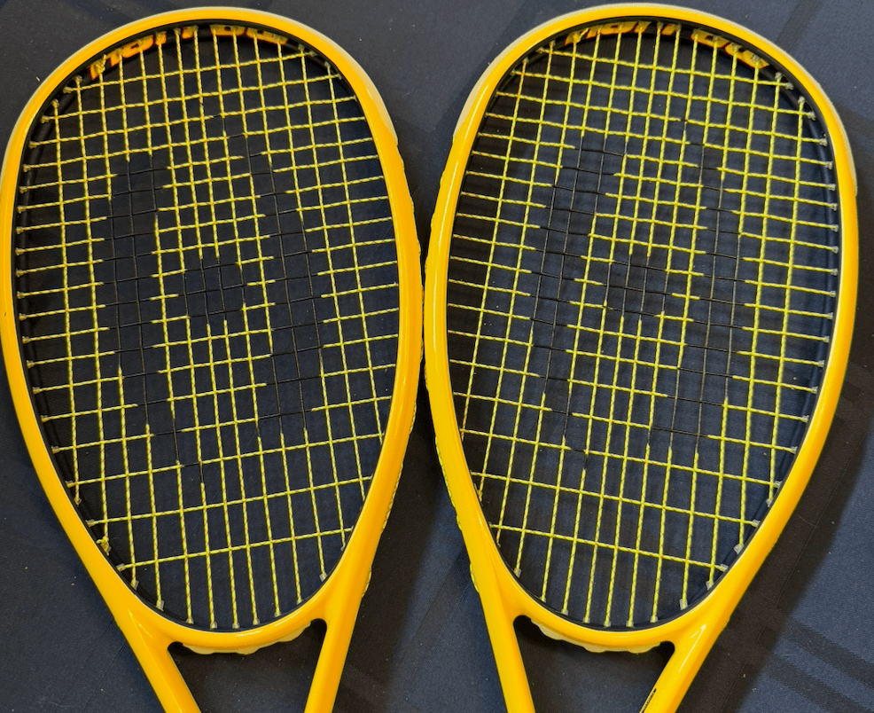 Two yellow squash racquets with matching prints on yellow strings